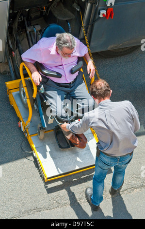 Vue supérieure de l'homme handicapé en fauteuil roulant d'être aidé sur l'entraîneur touriste rampe - France. Banque D'Images