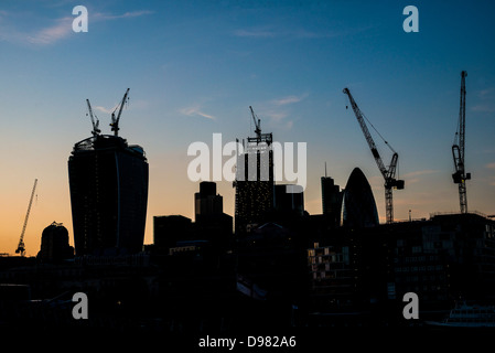 London Skyline construction grues Silhouette Londres // LONDRES, Royaume-Uni — L'horizon en évolution de Londres se silhouette de façon spectaculaire dans un ciel sombre, mettant en valeur la construction en cours de nouveaux gratte-ciel. Cette image saisissante reflète la croissance dynamique et l'ambition architecturale de la ville, avec les contours des immeubles en hauteur émergeants qui côtoient des monuments établis, symbolisant la transformation continue de Londres en tant que centre financier et culturel mondial. Banque D'Images