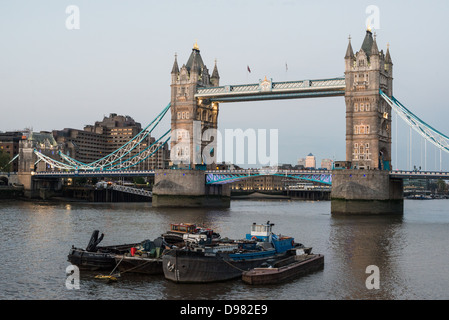 LONDRES, Royaume-Uni — Tower Bridge de Londres en début de soirée, avec des péniches sur la Tamise au premier plan. Construit à la fin des années 1800, le Tower Bridge orné est l'un des monuments emblématiques de Londres. Elle tire son nom de la tour de Londres, située à proximité, sur la rive nord de la Tamise. Banque D'Images