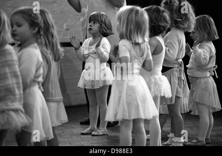 Trois et quatre ans, siffler les filles lors d'un groupe de danse ballet samedi matin dans le sud de Londres. À l'aide de focus sélectif, on voit plus clairement une jeune ballerine vêtue de childrens' tou-tou et chaussons de ballet au cours de cette classe de danse le samedi matin dans une église située près de leurs foyers respectifs. Banque D'Images