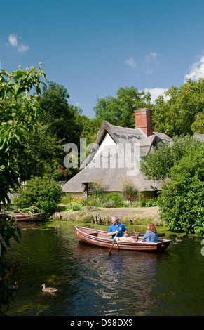 Un couple vu de bateau sur la rivière Stour par un chalet à Dedham. Banque D'Images