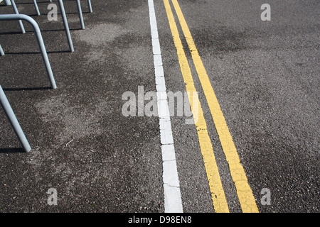 Détail de l'road montrant le blanc et jaune double lignes et rampes porte vélos sur le béton d'asphalte Banque D'Images