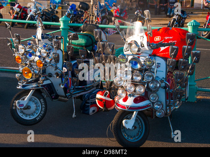 Une paire de mod scooters, ornée de plusieurs feux et rétroviseurs, garée près de la promenade de Brighton, Angleterre, Royaume-Uni. Banque D'Images