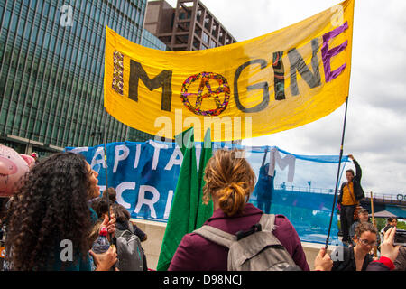 Londres, Royaume-Uni. 14 juin 2013. Une activiste optimiste bannière comme la dette de protestataires manifester à Canary Wharf en vue du sommet du G8 en Irlande du Nord. Crédit : Paul Davey/Alamy Live News Banque D'Images