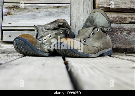 Old weathered chaussures de randonnée sur le porche en bois de l'Emporium Chitina, minuscule et la ville éloignée de Chitina, Alaska, USA Banque D'Images