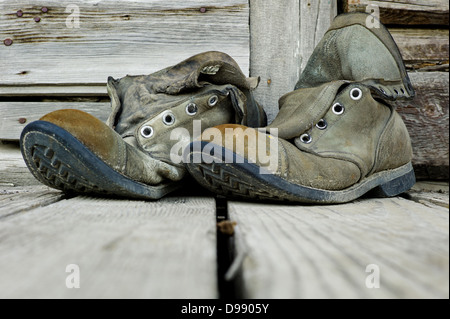 Old weathered chaussures de randonnée sur le porche en bois de l'Emporium Chitina, minuscule et la ville éloignée de Chitina, Alaska, USA Banque D'Images