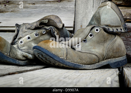 Old weathered chaussures de randonnée sur le porche en bois de l'Emporium Chitina, minuscule et la ville éloignée de Chitina, Alaska, USA Banque D'Images