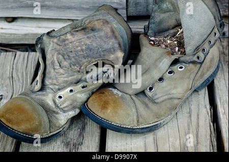 Old weathered chaussures de randonnée sur le porche en bois de l'Emporium Chitina, minuscule et la ville éloignée de Chitina, Alaska, USA Banque D'Images