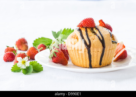 Muffins à la fraise avec une sauce au chocolat sur une plaque blanche Banque D'Images