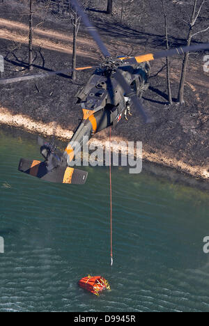 L'Armée américaine UN UH-60 Black Hawk comble un incendie de 500 gallons seau d'eau d'un lac pour combattre le feu de Forêt Noire le 12 juin 2013 près de Colorado Spring Co., l'incendie a tué deux personnes et détruit plus de 500 maisons de plus en plus destructrices de l'incendie dans le Colorado. s Banque D'Images