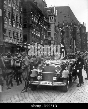 Adolf Hitler (1889 - 1945) née à l'Autrichienne, le Chancelier allemand, debout dans une voiture en tenant le salut à un défilé des troupes SA, Nuremberg, 1935. Fasciste Nazi Banque D'Images