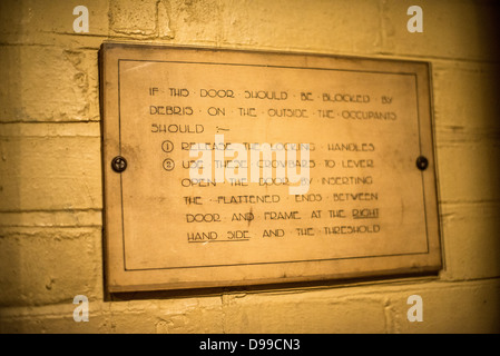 LONDRES, Royaume-Uni — Un panneau sur le mur détaillant comment s'échapper si des débris de bombes bloquent la porte des Churchill War Rooms à Londres. Le musée, l'une des cinq branches des musées de la guerre d'Imerial, conserve le bunker de commandement souterrain de la seconde Guerre mondiale utilisé par le premier ministre britannique Winston Churchill. Ses quartiers exigus ont été construits à partir d'un sous-sol de stockage converti dans le treasury Building à Whitehall, Londres. Étant souterrains, et sous un bâtiment exceptionnellement robuste, les chambres de guerre du Cabinet ont bénéficié d'une certaine protection contre les bombes tombant au-dessus pendant le Blitz. Banque D'Images