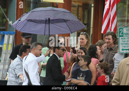 Shelburne Falls, Massachusetts, USA. 14 juin 2013. Au cours d'une douche à effet pluie, un assistant est titulaire d'un parapluie que Robert Downey Jr parle aux fans et signe des autographes sur l'ensemble de "le juge,' à Shelburne Falls, Massachusetts, le 14 juin 2013. Crédit : Susan Pease/Alamy Live News Banque D'Images