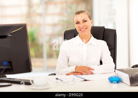 Senior businesswoman sitting in front of desk in office Banque D'Images