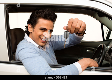 Smiling man sitting in a car et montrant car key Banque D'Images