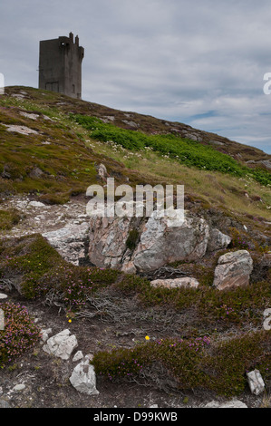 Malin Head Tour, comté de Donegal, sur horizon contre ciel gris, avec des rochers en premier plan. Banque D'Images