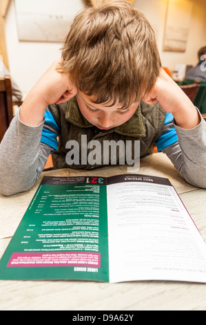 Un garçon de 9 ans regarde le menu dans Byfords cafe à Holt , Norfolk , Angleterre , Angleterre , Royaume-Uni Banque D'Images