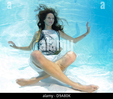 Une jeune femme en robe blanche flotte sous l'eau autorisation Modèle disponible Banque D'Images