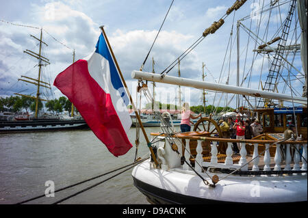 Rouen, France. 15 Juin, 2013. Drapeau français sur bateau en bois à l'Armada de Rouen. Femme à la barre et grands voiliers en arrière-plan. Crédit : Christine Gates/Alamy Live News Banque D'Images