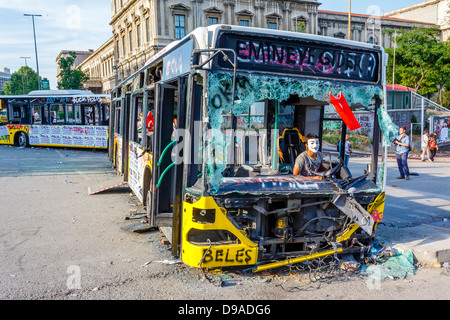 Jeune homme portant un masque anonyme et les bus détruit lors de Taksim Gezi Parkı protestations, Istanbul, Turquie Banque D'Images