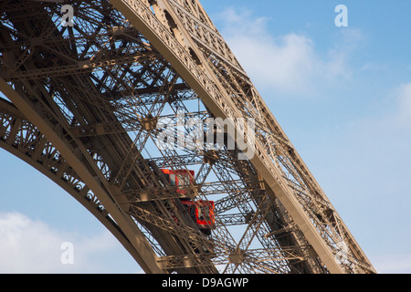 Deux ascenseurs rouge vif grimpant sur l'une des poutres de fer de la Tour Eiffel ce qui porte les touristes à l'étage Banque D'Images