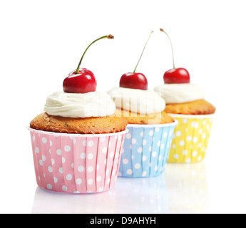 Cupcakes avec de la crème fouettée et de cerises isolé sur fond blanc Banque D'Images