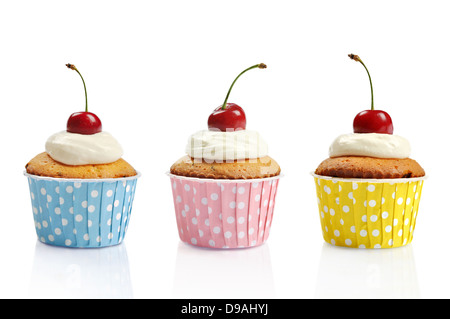 Trois cupcakes avec de la crème fouettée et des cerises isolé sur fond blanc Banque D'Images