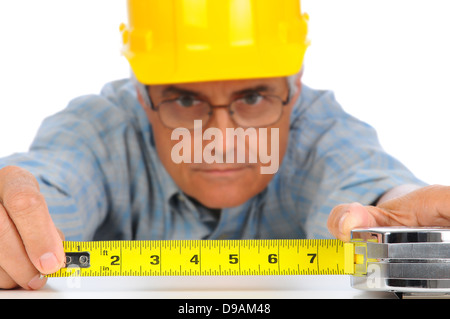 Libre de construction worker in hard hat en utilisant un ruban à mesurer avec les numéros vers l'avant. Banque D'Images