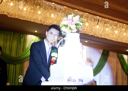 Le mariage chinois, le marié couper le gâteau dans la scène. Banque D'Images