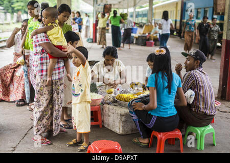 Yangon, Union du Myanmar. 15 Juin, 2013. Les gens achètent des collations pendant l'attente pour le train circulaire dans la gare de Yangon. Circulaire de Yangon fer est le réseau ferroviaire suburbain local qui dessert la région métropolitaine de Yangon. Exploité par les chemins de fer, le Myanmar 45,9 kilomètres (28,5Â mi) 39-station système boucle relie des villes satellites et les banlieues de la ville. Le chemin de fer a environ 200 entraîneurs, s'exécute 20 fois et vend 100 000 à 150 000 billets par jour. La boucle, qui prend environ trois heures, est populaire pour les touristes de voir une section transversale de la vie à Yangon. Les trains à partir de 3:45 Banque D'Images