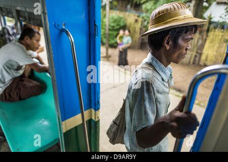 Yangon, Union du Myanmar. 15 Juin, 2013. Un homme s'apprête à descendre le train Yangon comme il tire circulaire dans son arrêt. La Circulaire de Yangon est le chemin de fer réseau ferroviaire suburbain local qui dessert la région métropolitaine de Yangon. Exploité par les chemins de fer, le Myanmar 45,9 kilomètres (28,5Â mi) 39-station système boucle relie des villes satellites et les banlieues de la ville. Le chemin de fer a environ 200 entraîneurs, s'exécute 20 fois et vend 100 000 à 150 000 billets par jour. La boucle, qui prend environ trois heures, est populaire pour les touristes de voir une section transversale de la vie à Yangon. Les trains depuis 3 Banque D'Images