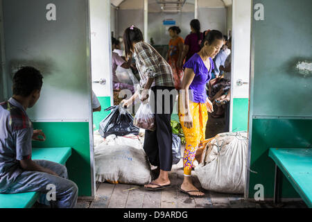 Yangon, Union du Myanmar. 15 Juin, 2013. Les femmes l'étape dans la porte de l'avant train circulaire de Yangon la tire dans leur station. La Circulaire de Yangon est le chemin de fer réseau ferroviaire suburbain local qui dessert la région métropolitaine de Yangon. Exploité par les chemins de fer, le Myanmar 45,9 kilomètres (28,5Â mi) 39-station système boucle relie des villes satellites et les banlieues de la ville. Le chemin de fer a environ 200 entraîneurs, s'exécute 20 fois et vend 100 000 à 150 000 billets par jour. La boucle, qui prend environ trois heures, est populaire pour les touristes de voir une section transversale de la vie à Yangon. T Banque D'Images