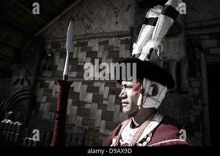 Guerrier Tribal Naga debout avec une lance à l'extérieur d'une cabane, Hornbill Festival, Kohima, Nagaland, Inde Banque D'Images