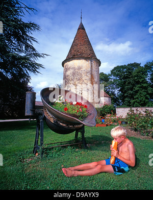 Le château de la Berchère. Un garçon de sept manger une baguette, assise seule dans le jardin d'un chateau hotel en Bourgogne, France, Europe. Banque D'Images