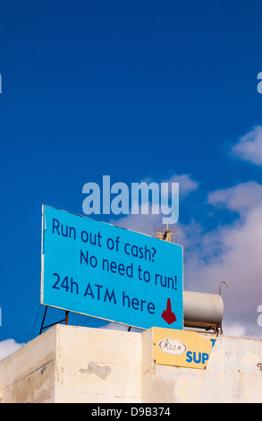 Panneau ATM de 24 heures sur le toit d'un bâtiment de rendu blanc placé contre un ciel bleu. Banque D'Images