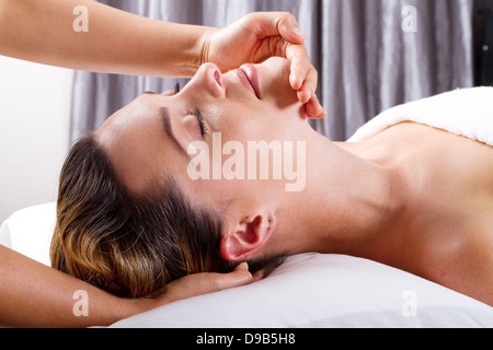Jolie jeune femme qui reçoit un massage de la tête au salon de Banque D'Images