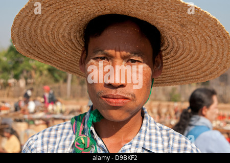 Birman jeune homme portant un chapeau de paille et de mâcher de la noix de bétel dans un marché encombré le Myanmar (Birmanie) Banque D'Images