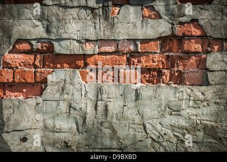 Un vieux mur de briques rouges en terre cuite érodé avec fond en plâtre cassé. Banque D'Images