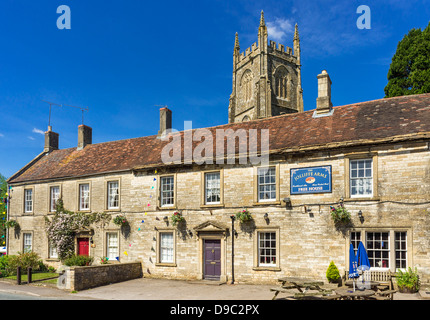 Le pub du village anglais - Armes à Kilmersdon Jolliffe, Somerset, England, UK - avec derrière l'église Banque D'Images