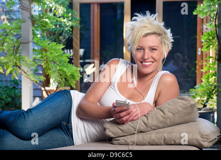 Young woman on sofa à écouter de la musique Banque D'Images