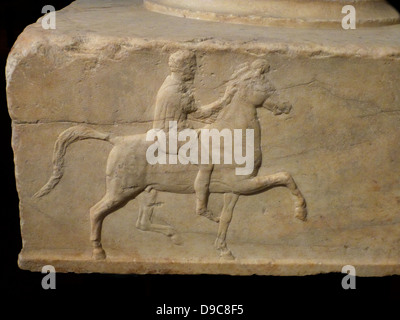 Base d'un dévouement en marbre. On trouve dans l'Agora athénienne. Base d'un dévouement pour les victoires dans le combat de cavalerie maquette concours. Trois côtés de celui-ci ont reliefs représentant un cavalier à cheval vers un trépied. L'inscription sur le quatrième côté fournit le nom des dedicators victorieux et également celle de l'Bryavis sculpteur qui a sculpté le monument. Il aura appuyé un trépied de bronze consacré par les vainqueurs. Milieu du 4e siècle avant J.-C.. Banque D'Images