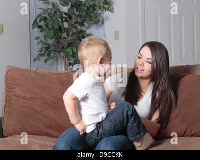 Mère et son jeune fils assis sur le canapé à la maison dans le style de vie décontracté de jouer ensemble et le collage d'amour Banque D'Images