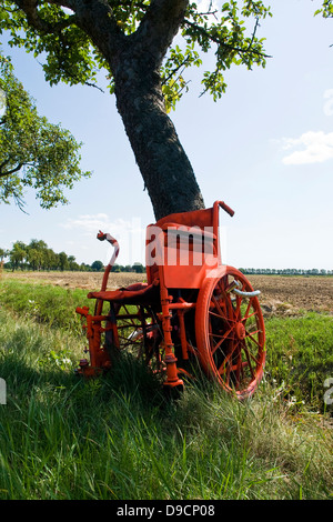 Chaise de roue dans un arbre comme un avertissement pour les motocyclistes déménagement trop rapidement, un fauteuil roulant à un arbre ace un avertissement pour voyager trop un Banque D'Images