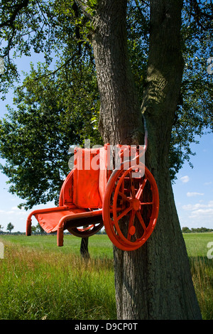 Chaise de roue dans un arbre comme un avertissement pour les motocyclistes déménagement trop rapidement, un fauteuil roulant à un arbre ace un avertissement pour voyager trop un Banque D'Images