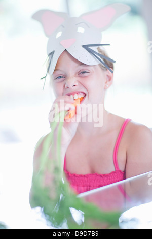 Fille en costume de lapin carotte manger Banque D'Images