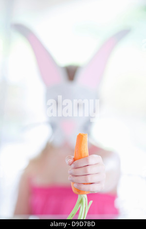 Fille en costume de lapin carotte manger Banque D'Images