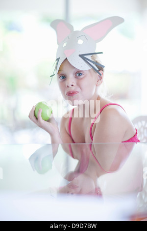 Fille en costume de lapin eating apple Banque D'Images