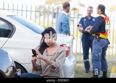 Femme photographiant dégâts sur sa voiture au lieu de l'accident de voiture Banque D'Images