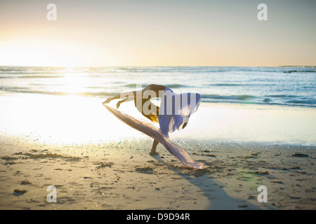 Jeune femme dansant sur la plage ensoleillée Banque D'Images