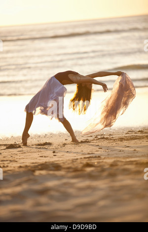 Jeune femme dansant sur la plage ensoleillée Banque D'Images